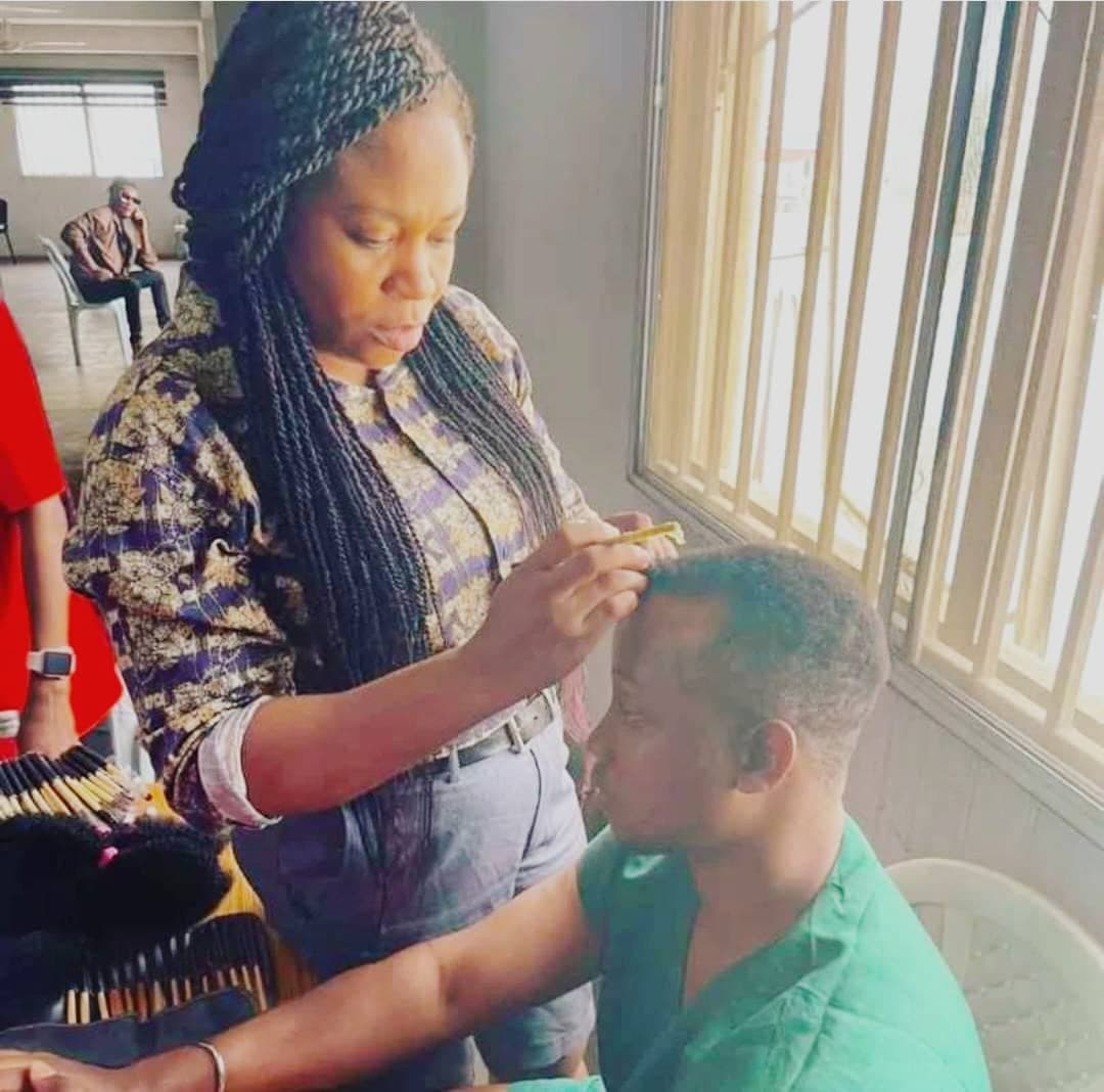 Hair stylist preparing an actor beside a window before filming