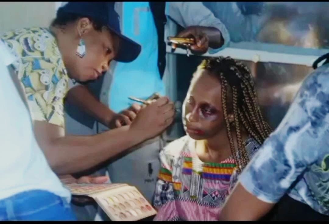Makeup artist applying character makeup to a seated actor